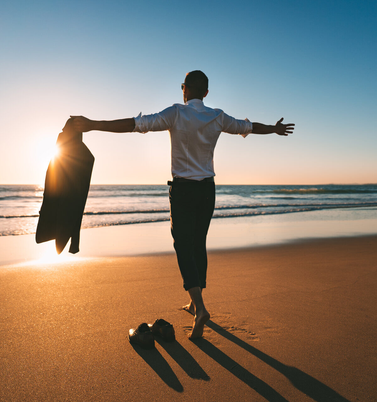 Das Leben ist schön. Mann mit offenen Armen genießt das Leben und die Freiheit am Strand mit Sonnenuntergang