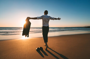 Das Leben ist schön. Mann mit offenen Armen genießt das Leben und die Freiheit am Strand mit Sonnenuntergang