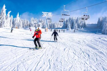 Menschen genießen Skifahren und Snowboarden im Bergskigebiet mit wunderschöner Winterlandschaft im Hintergrund