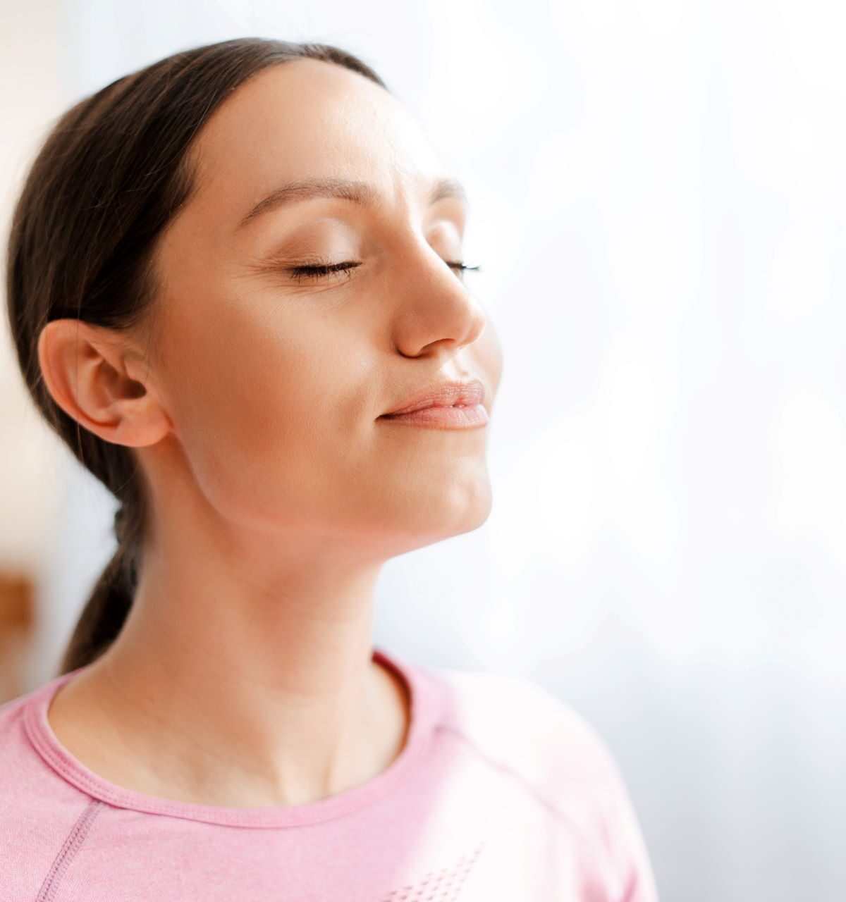 Frau mit geschlossenen Augen, die atmet, während sie sich nach dem Training entspannt und sich von den Übungen zu Hause erholt