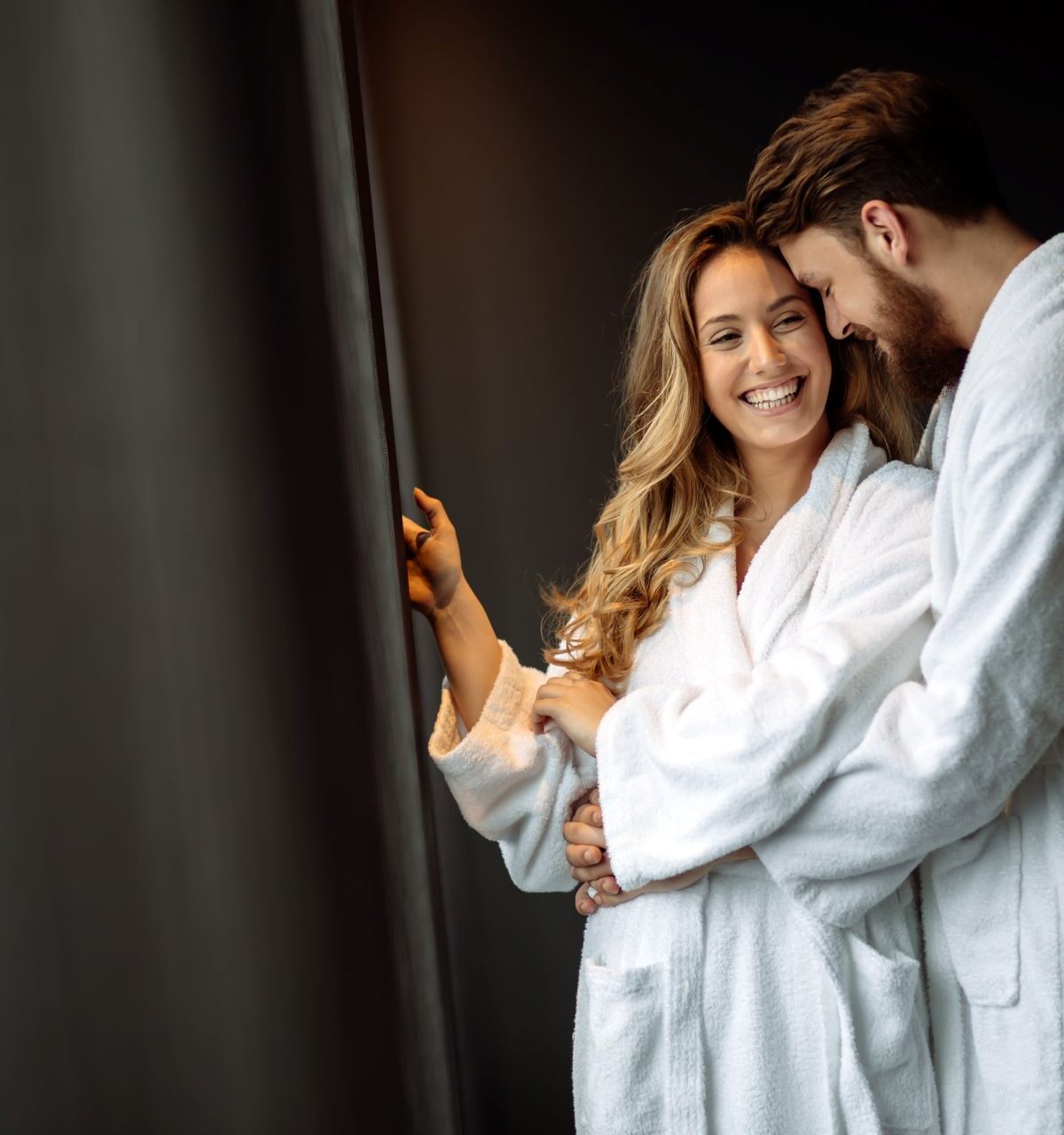 Ein glückliches Paar in weißen Bademänteln genießt ein Wellness-Retreat, begleitet von Amorette International, das für exklusive und stilvolle Erholung sorgt.