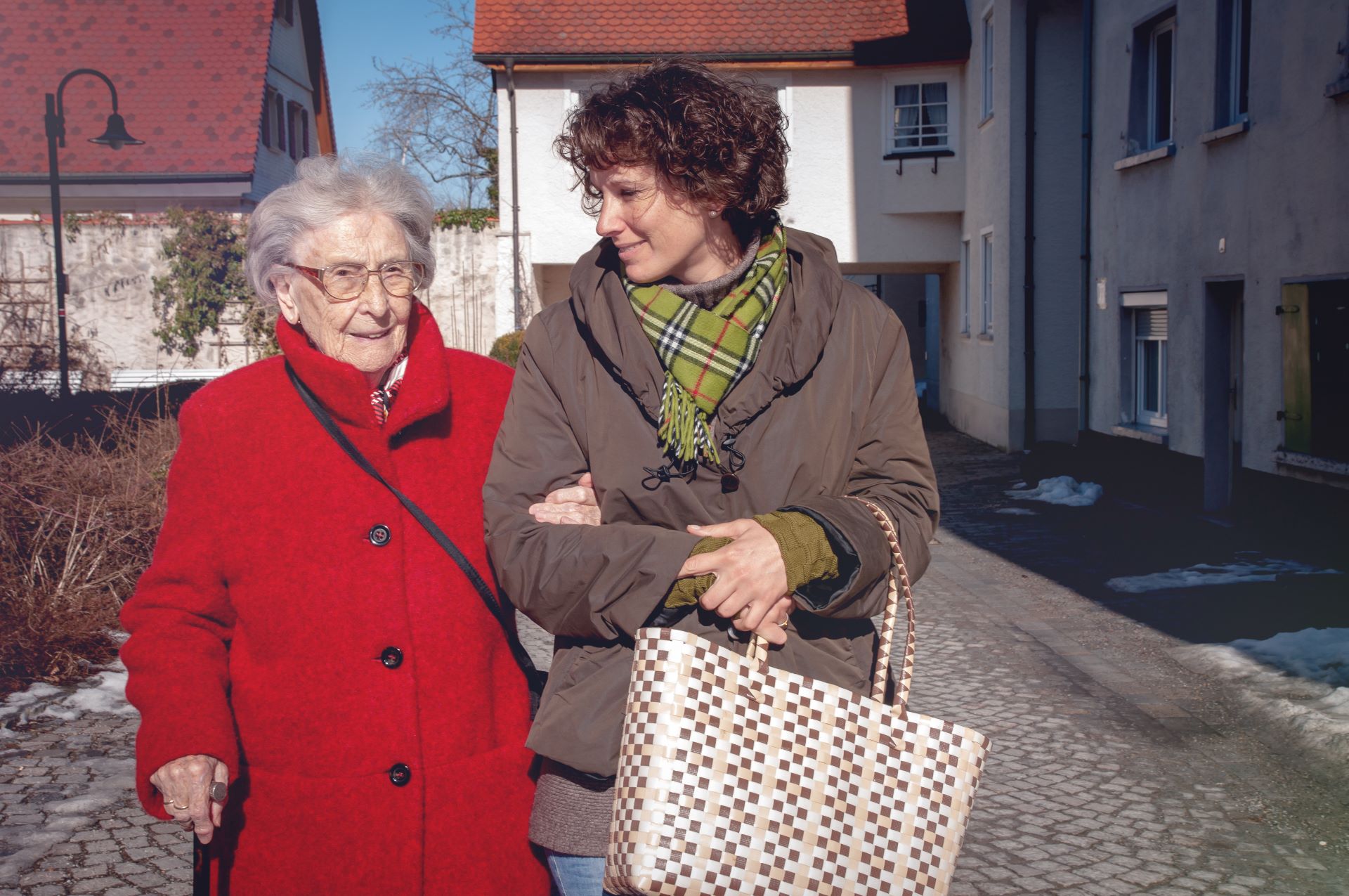 Seniorin wird bei einem Spaziergang von einer Haushaltshilfe begleitet