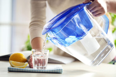 Eine Frau gießt sich Wasser aus einem Wasserfilter