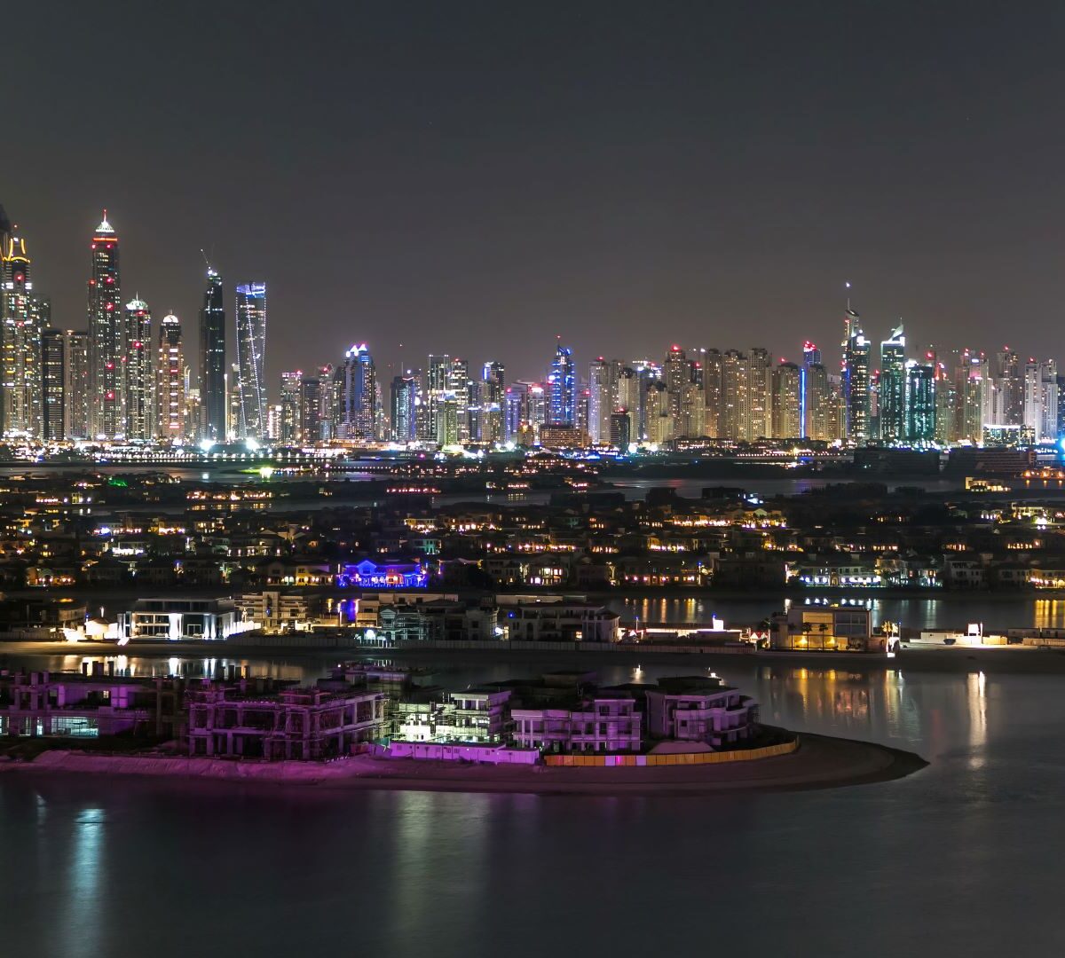 Dubai-Skyline bei Nacht mit Blick auf das Meer.