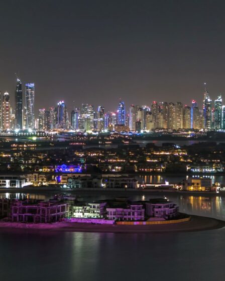 Dubai-Skyline bei Nacht mit Blick auf das Meer.