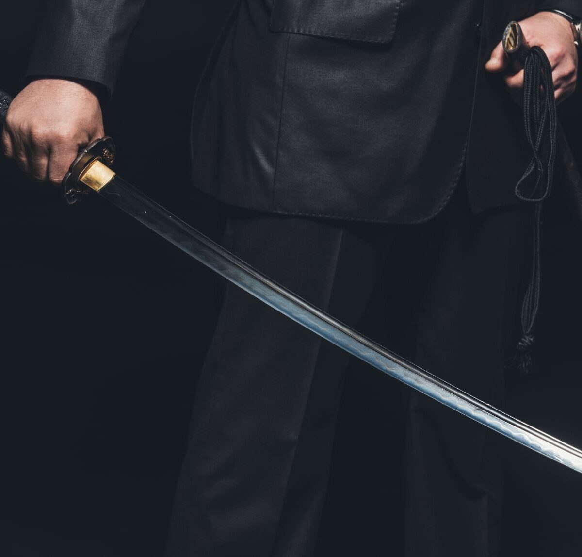 Person hält ein geschliffenes Katana mit verziertem Griff in der Hand, das Tradition, Präzision und japanische Schmiedekunst vereint.