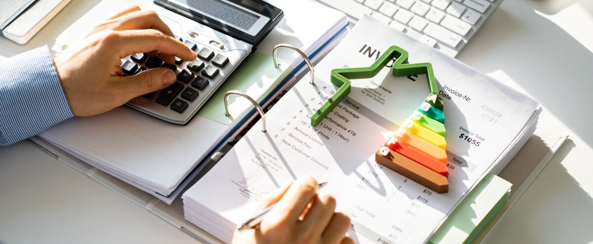 Energieberater Ausbildung: Mann mit Taschenrechner berechnet Kosten und Energieeffizienz anhand von Unterlagen und Diagramm