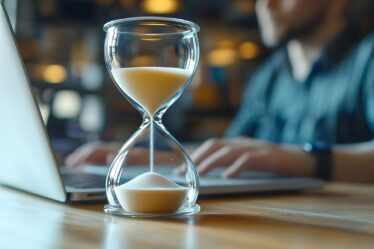 Sanduhr auf Schreibtisch vor Laptop | AMZ Agentur